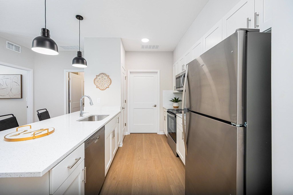 A modern kitchen with a stainless steel refrigerator and wooden floors.
