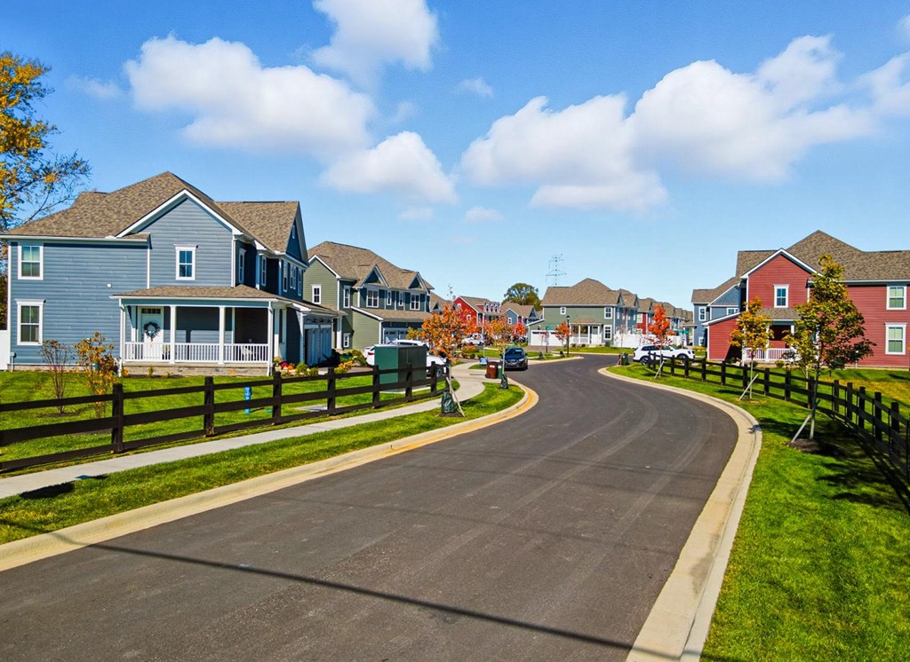 A residential street with houses on both sides and a clear blue sky above.