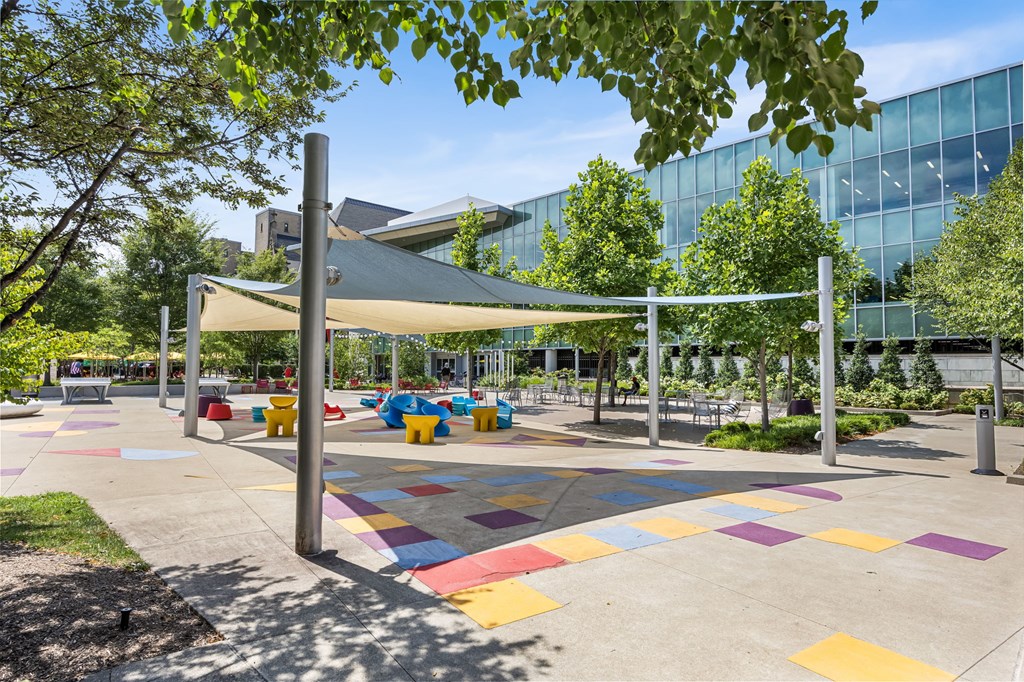 A playground with a white canopy and colorful tiles on the ground.