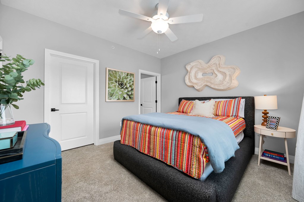 A bedroom with a bed, nightstand, and a ceiling fan.