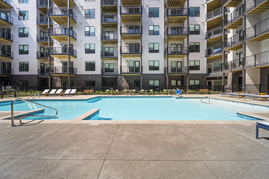 A large swimming pool in front of a multi-story apartment building.