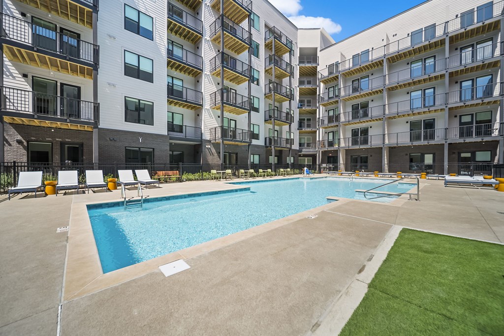 A large swimming pool is surrounded by apartment buildings.