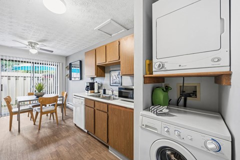 A small kitchen with a washing machine on top of the counter.