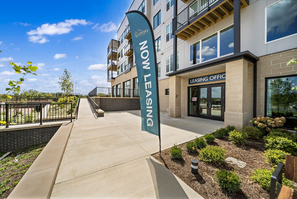 A building with a leasing office and a sign that says "Now Leasing".