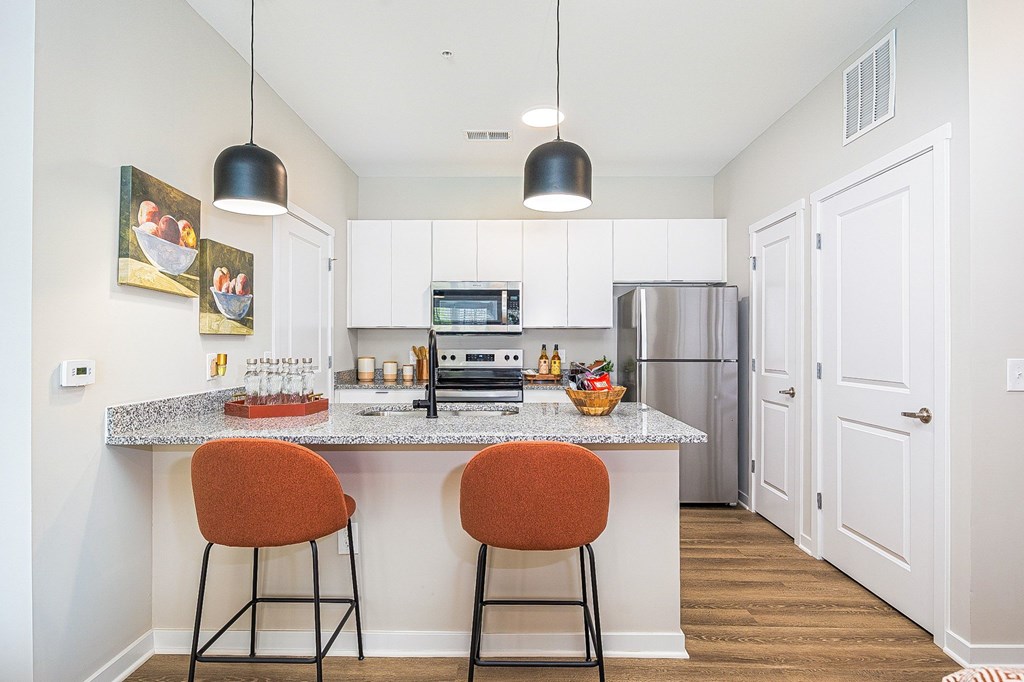 A kitchen with a white countertop and orange barstools.