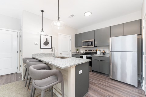 A kitchen with a white counter top and grey chairs.