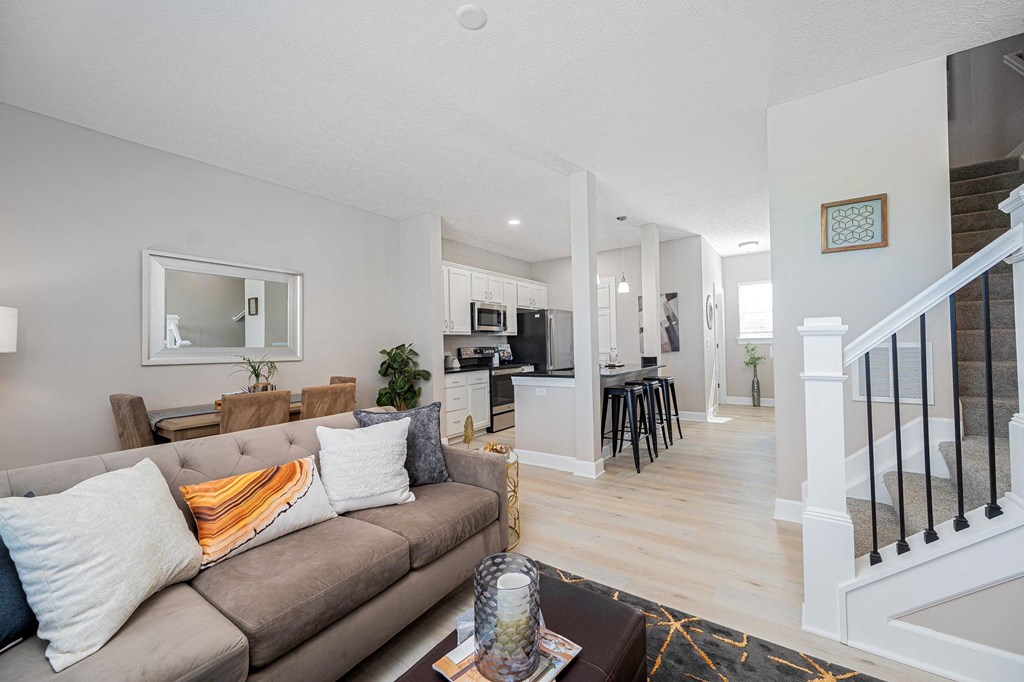 a living room with a couch and a kitchen with a staircase