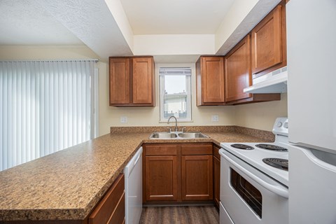A kitchen with brown cabinets and a white stove top oven.