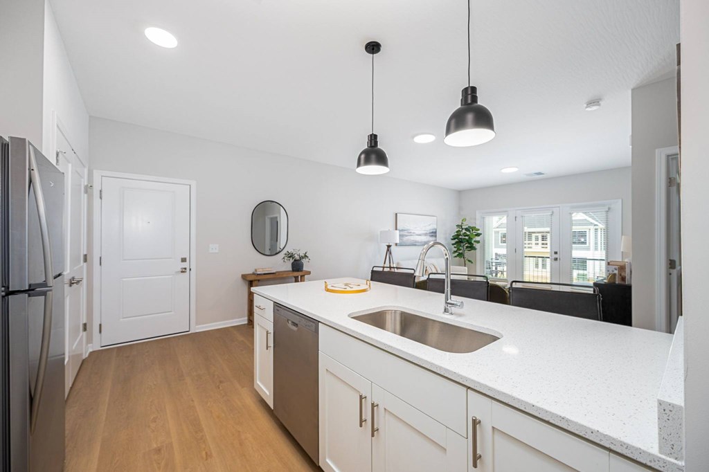 A kitchen with white countertops and wooden floors.