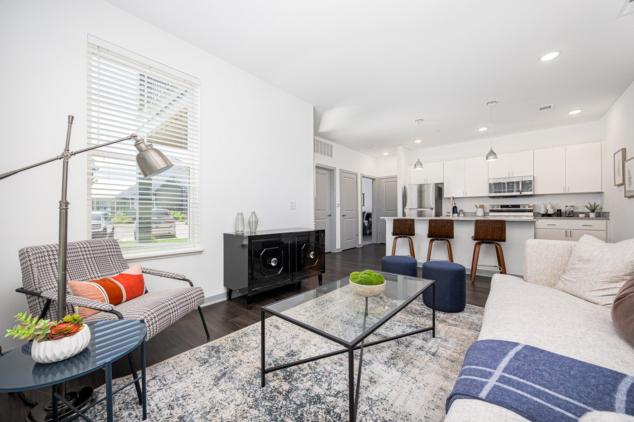 A modern living room with a glass coffee table and a grey sofa.