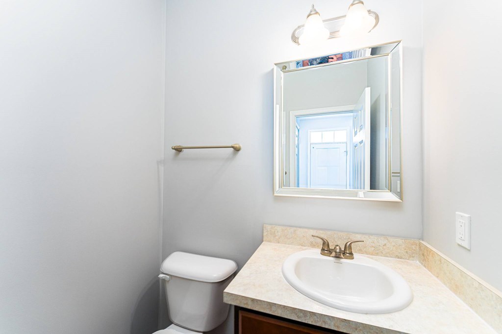 A bathroom with a toilet, sink and mirror.