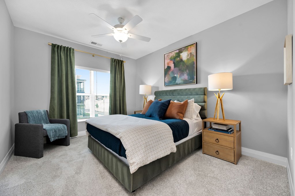 A bedroom with a bed, chair, and a painting on the wall.