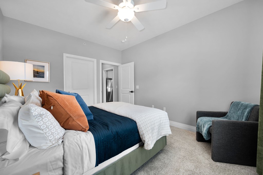 A bedroom with a bed, a chair, and a ceiling fan.