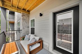 A balcony with a white couch and a wooden table.