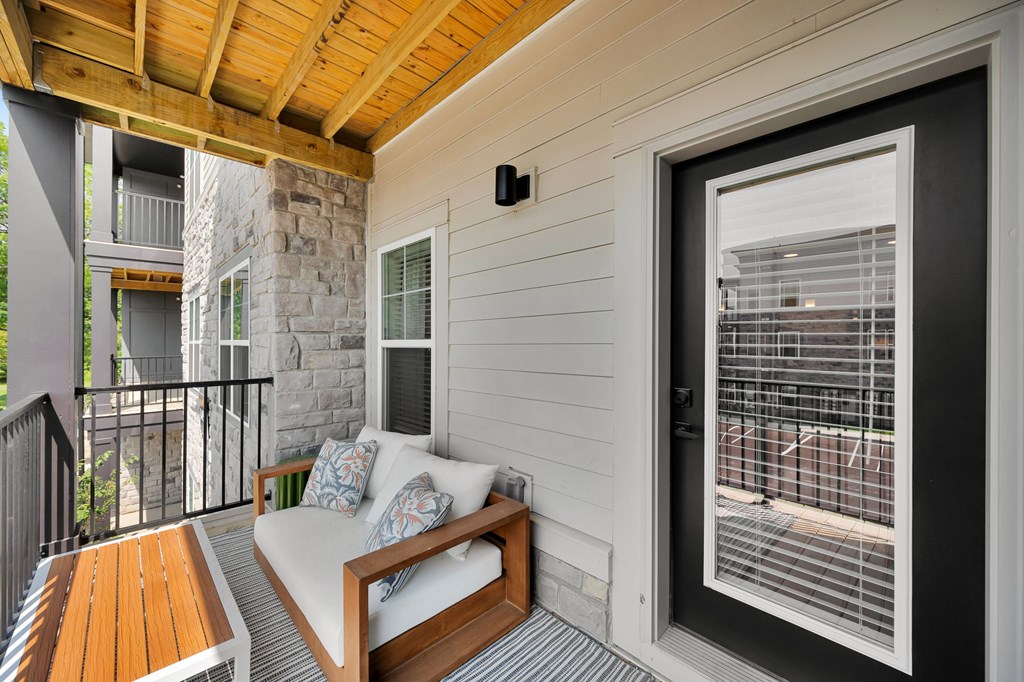 A balcony with a white couch and a wooden table.
