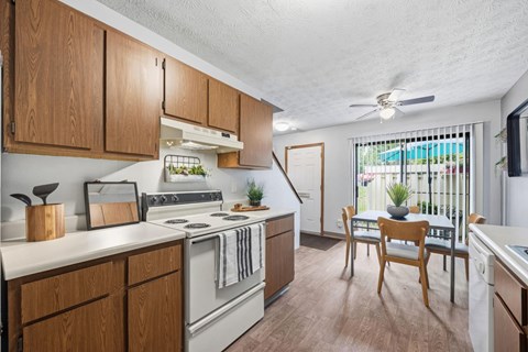 A kitchen with wooden cabinets and a white stove top oven.