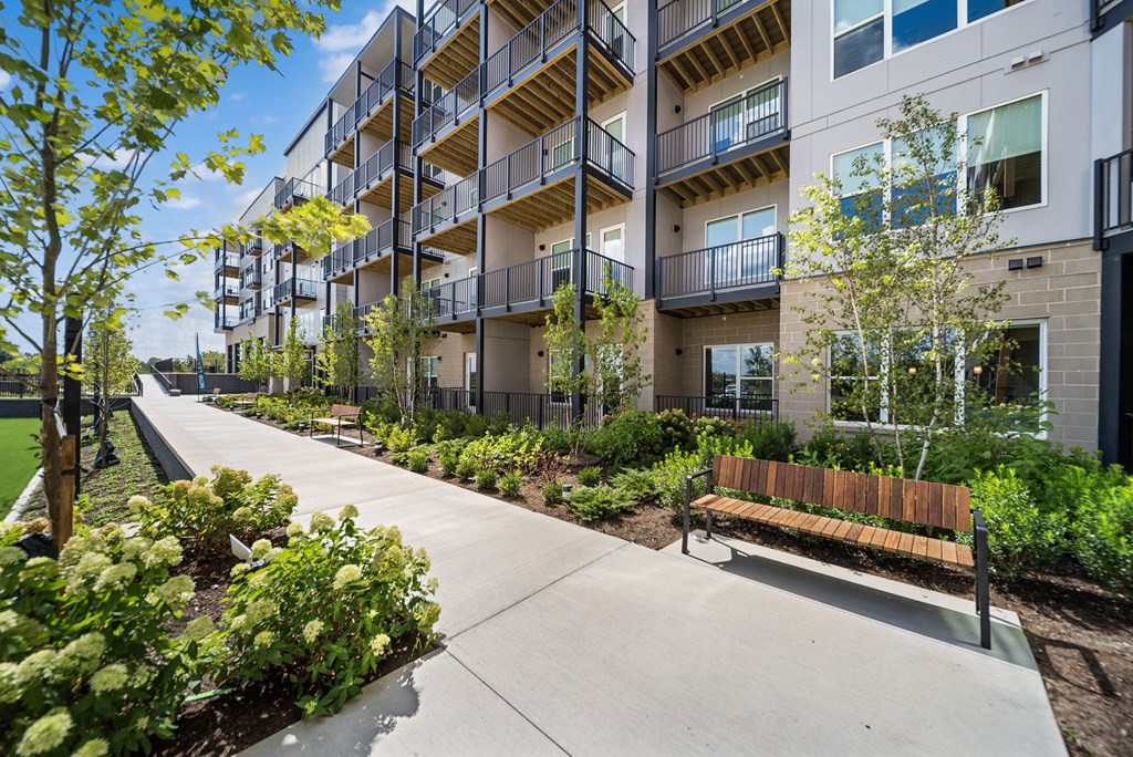 A long concrete walkway leads to apartment buildings with balconies.