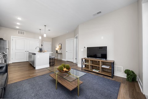 A modern living room with a glass coffee table and a bowl of fruit on it.