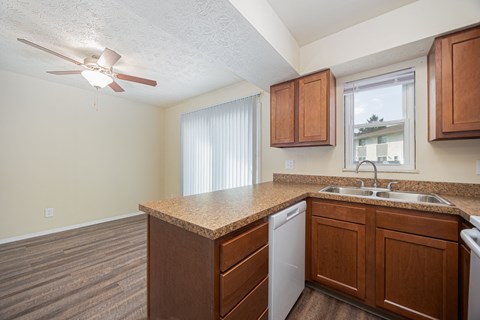 A kitchen with a white ceiling fan and wooden cabinets.
