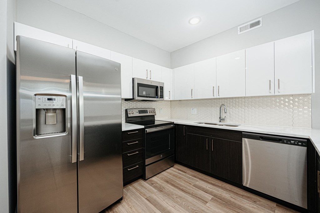 a modern kitchen with stainless steel appliances and white cabinets