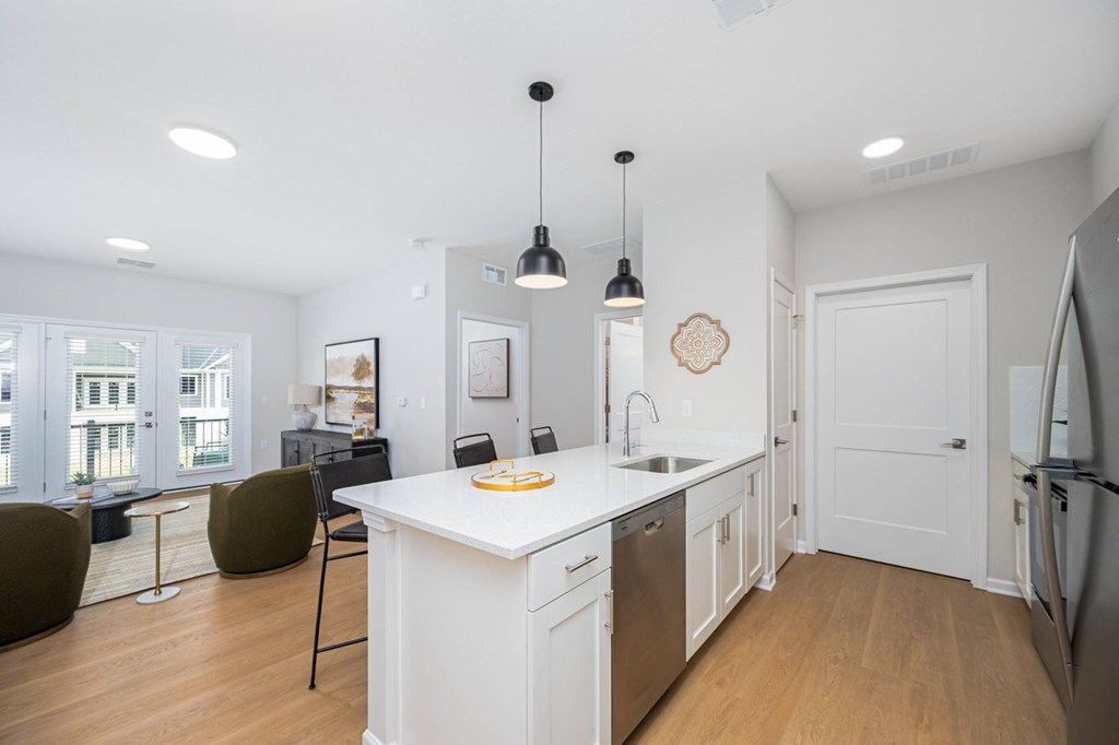 A kitchen with white cabinets and a white island with a sink.