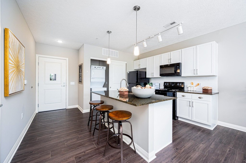 a kitchen with white cabinets and a bar with three stools