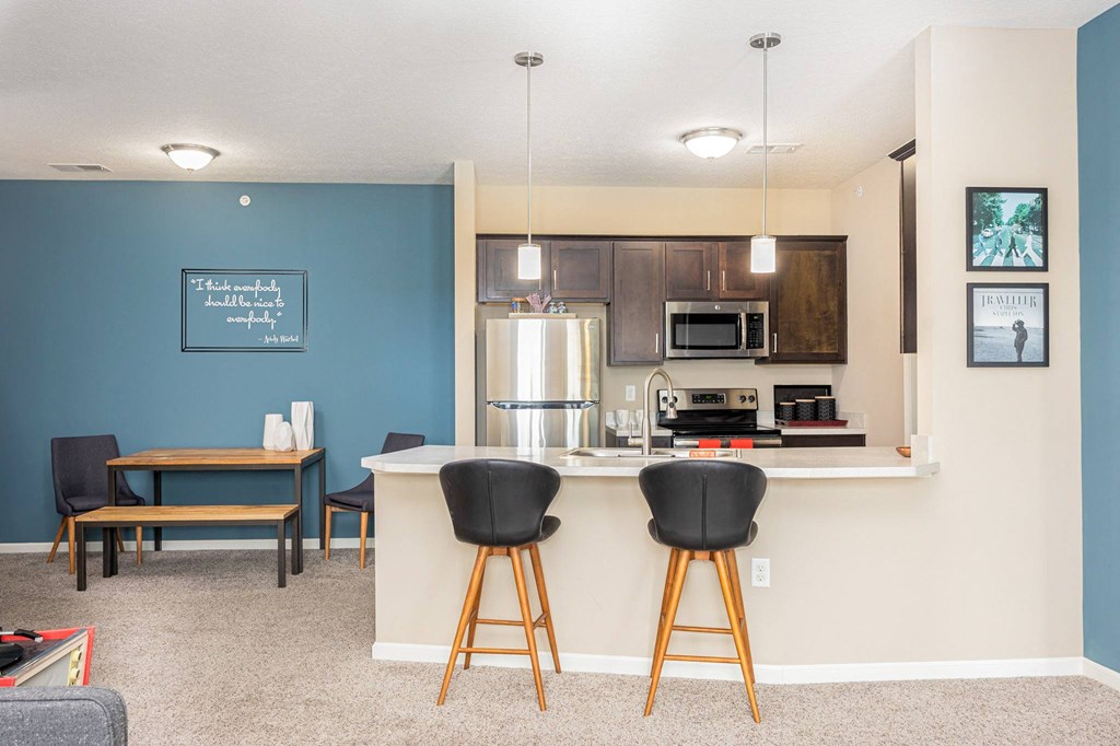 a kitchen with a bar and a living room with a table and chairs