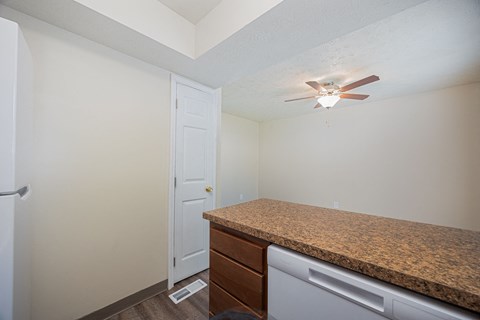 A kitchen with a counter and a fan on the ceiling.