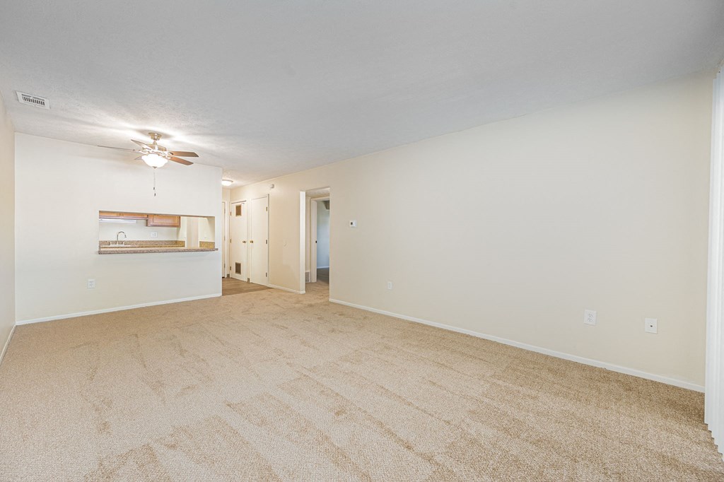 a spacious living room with carpet and a ceiling fan
