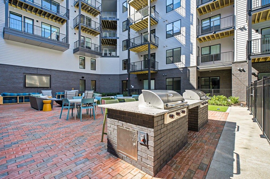 A brick BBQ grill is in the middle of a patio.