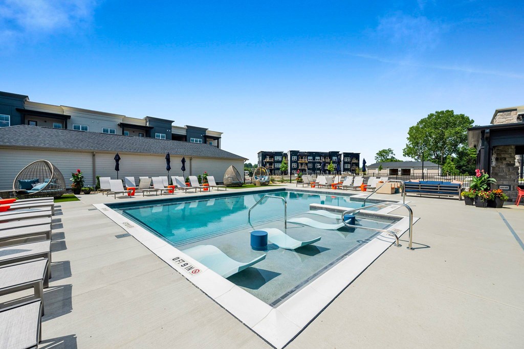 A large outdoor swimming pool with lounge chairs around it.