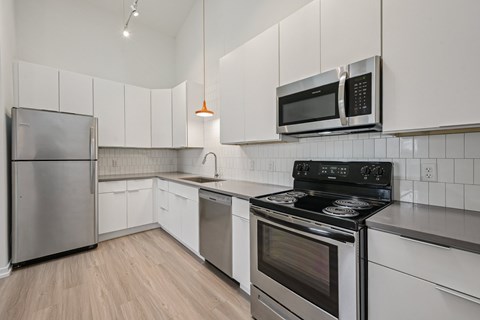 A kitchen with a stove, microwave, and refrigerator.