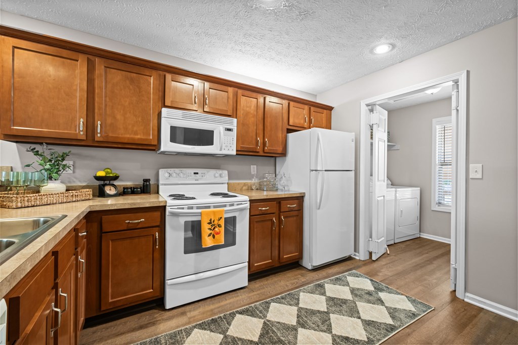 A kitchen with white appliances and wooden cabinets.