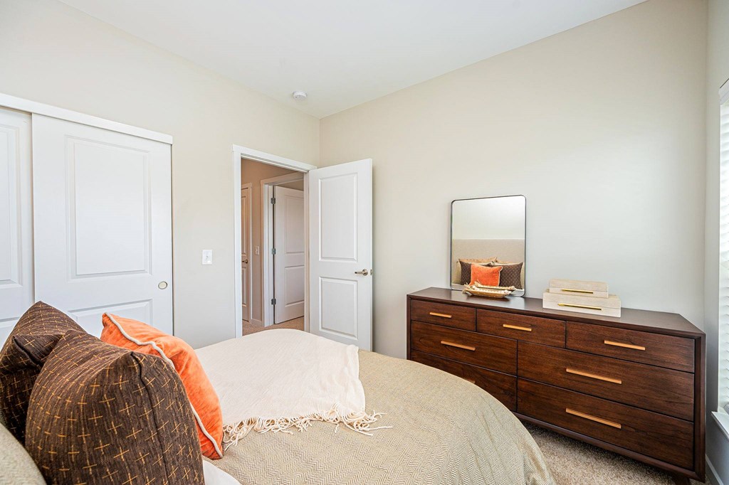 A bedroom with a bed, dresser, and mirror.