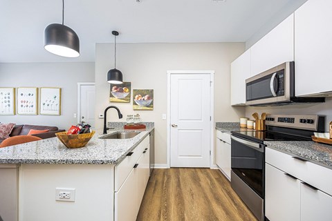 A kitchen with white cabinets and a granite countertop.