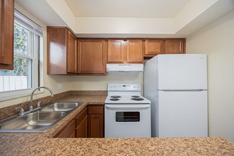 A kitchen with a stove, sink, and refrigerator.