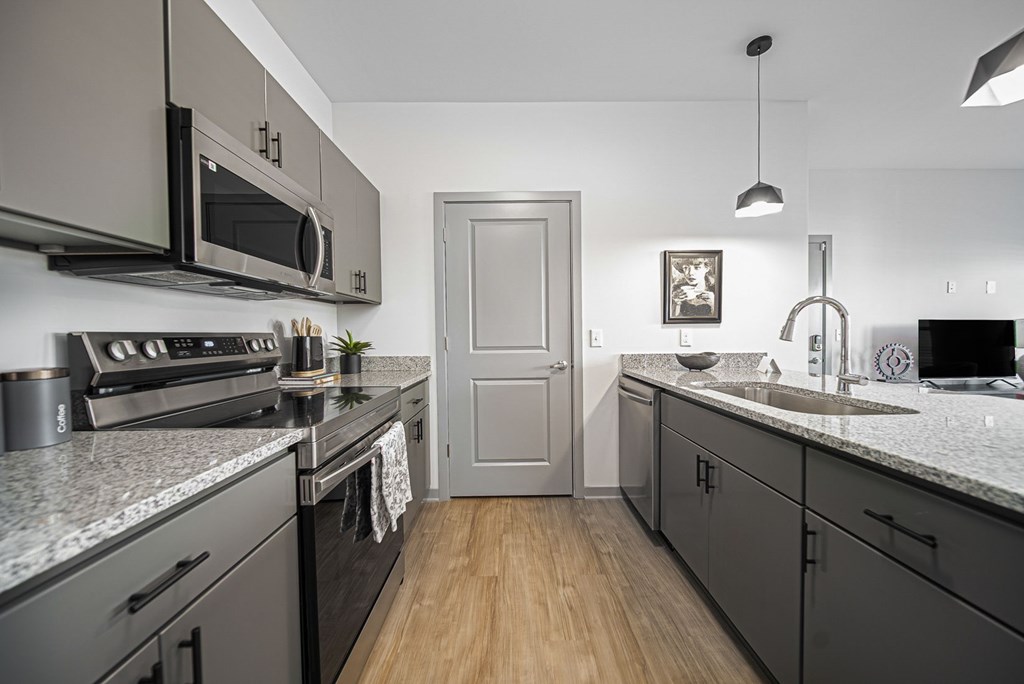 A kitchen with a grey theme and a wooden floor.