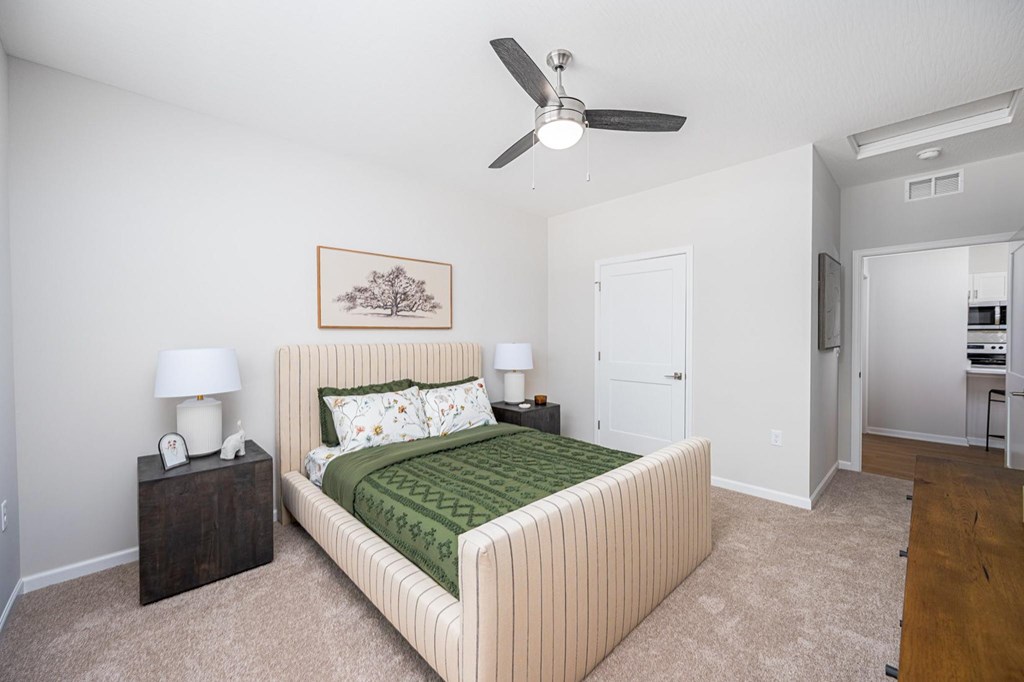 A bedroom with a bed, nightstands, and a ceiling fan.