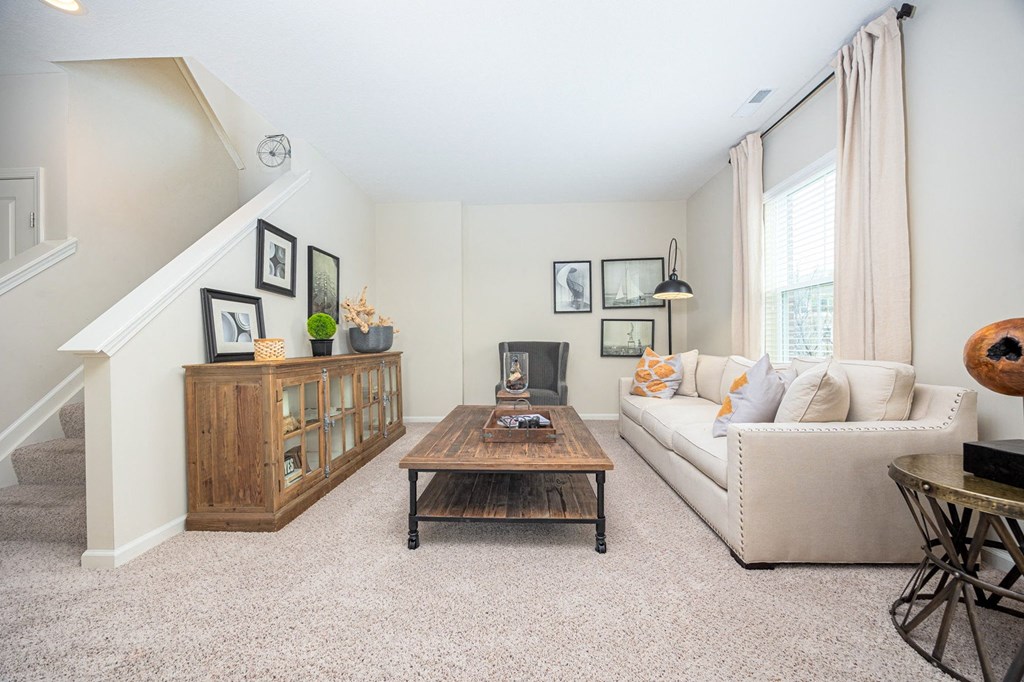 A living room with a couch, coffee table, and staircase.