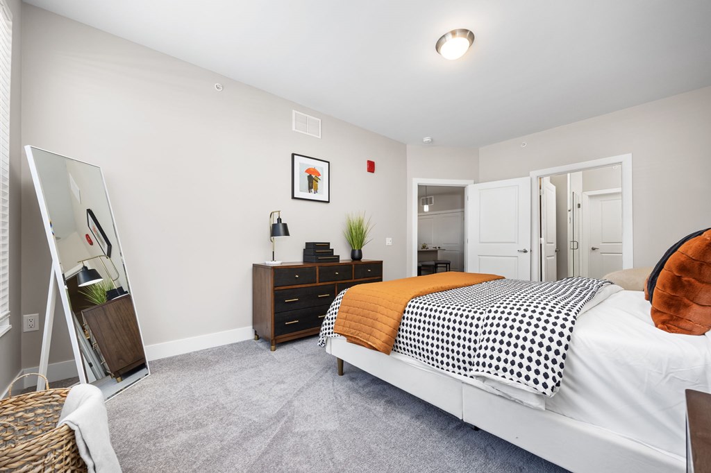 A bedroom with a bed, dresser, and mirror.