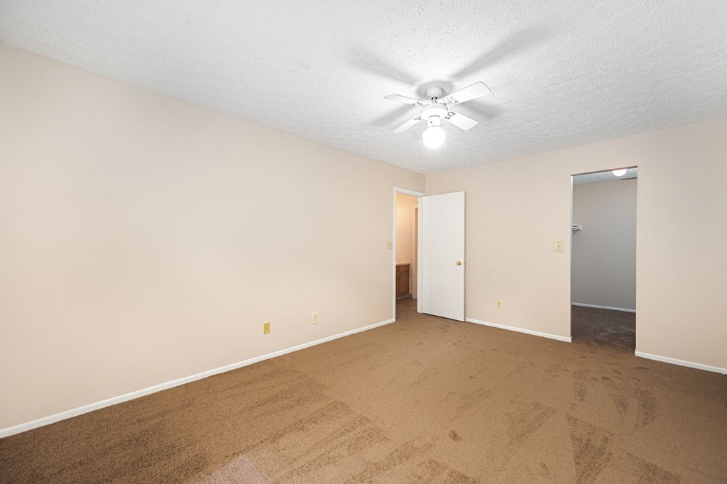 a spacious living room with carpet and a ceiling fan