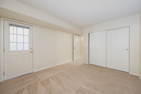 an empty living room with a door to a closet