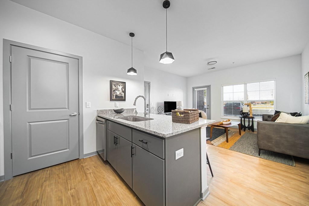 A kitchen with a white counter top and grey cabinets.