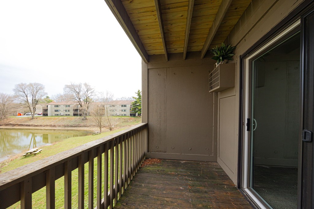 A balcony with a glass door leading to a room.