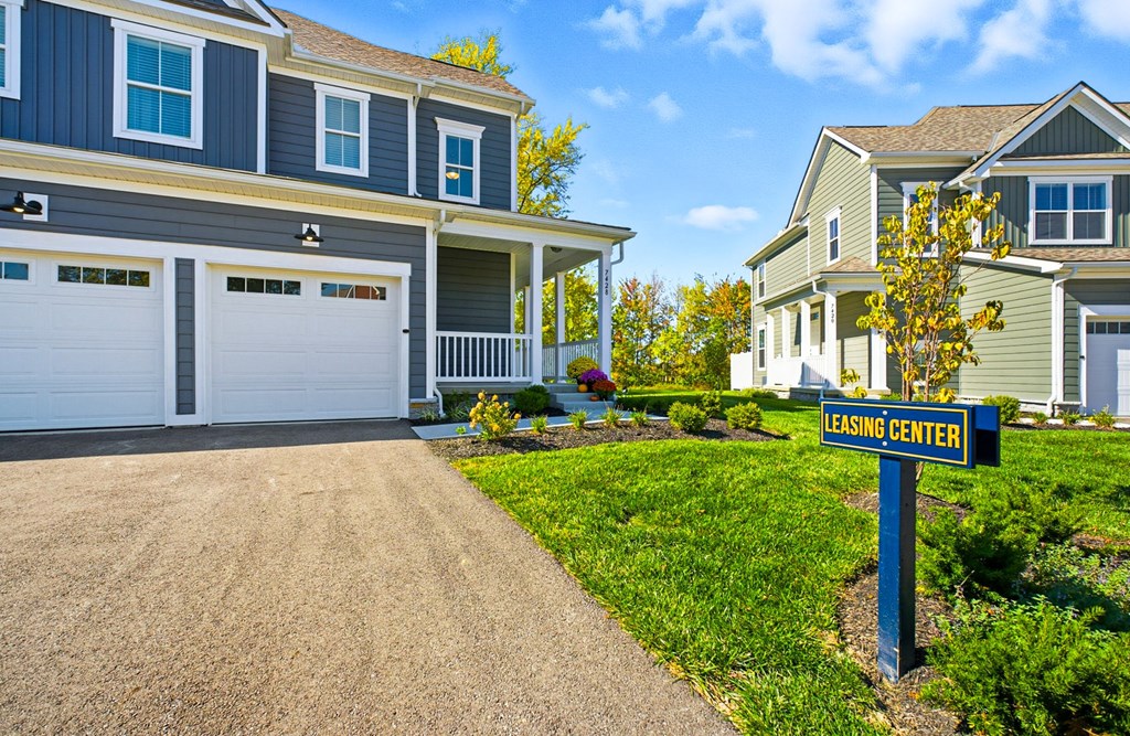 A leasing center sign is in front of a two-story house with a garage.