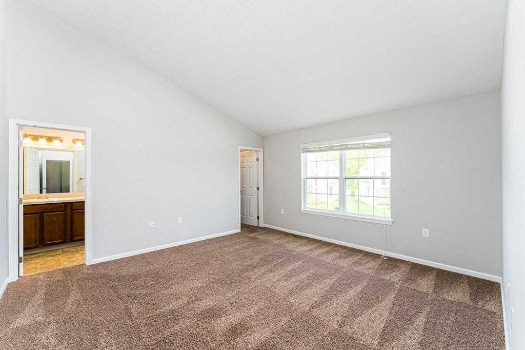 A room with a carpeted floor and a window.