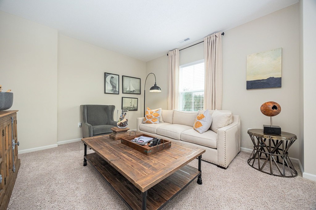 A living room with a white couch, a wooden coffee table, and a grey armchair.