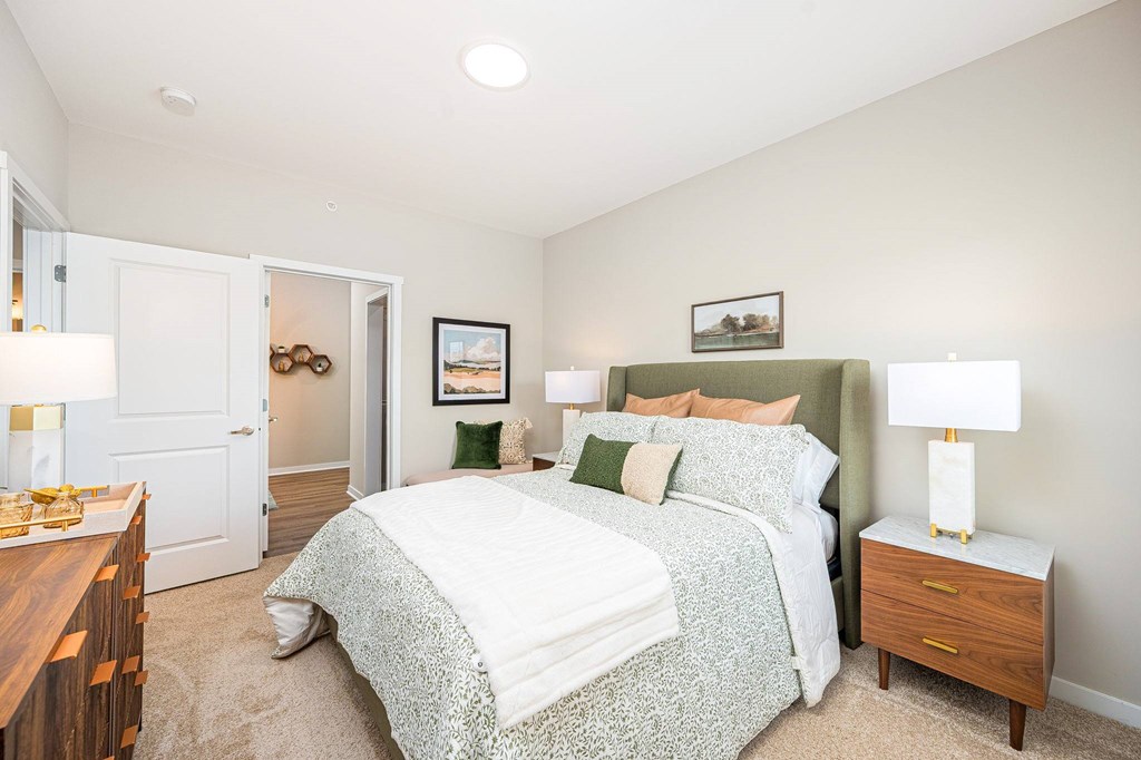 A bedroom with a bed, nightstand, and a painting on the wall.