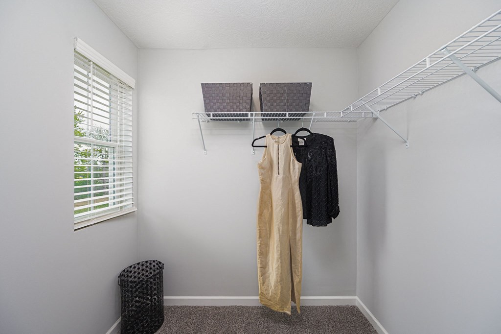a walk in closet with a clothes rack and a window