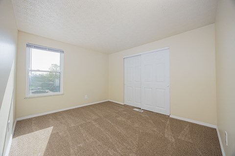 A room with a white door and carpeted floor.